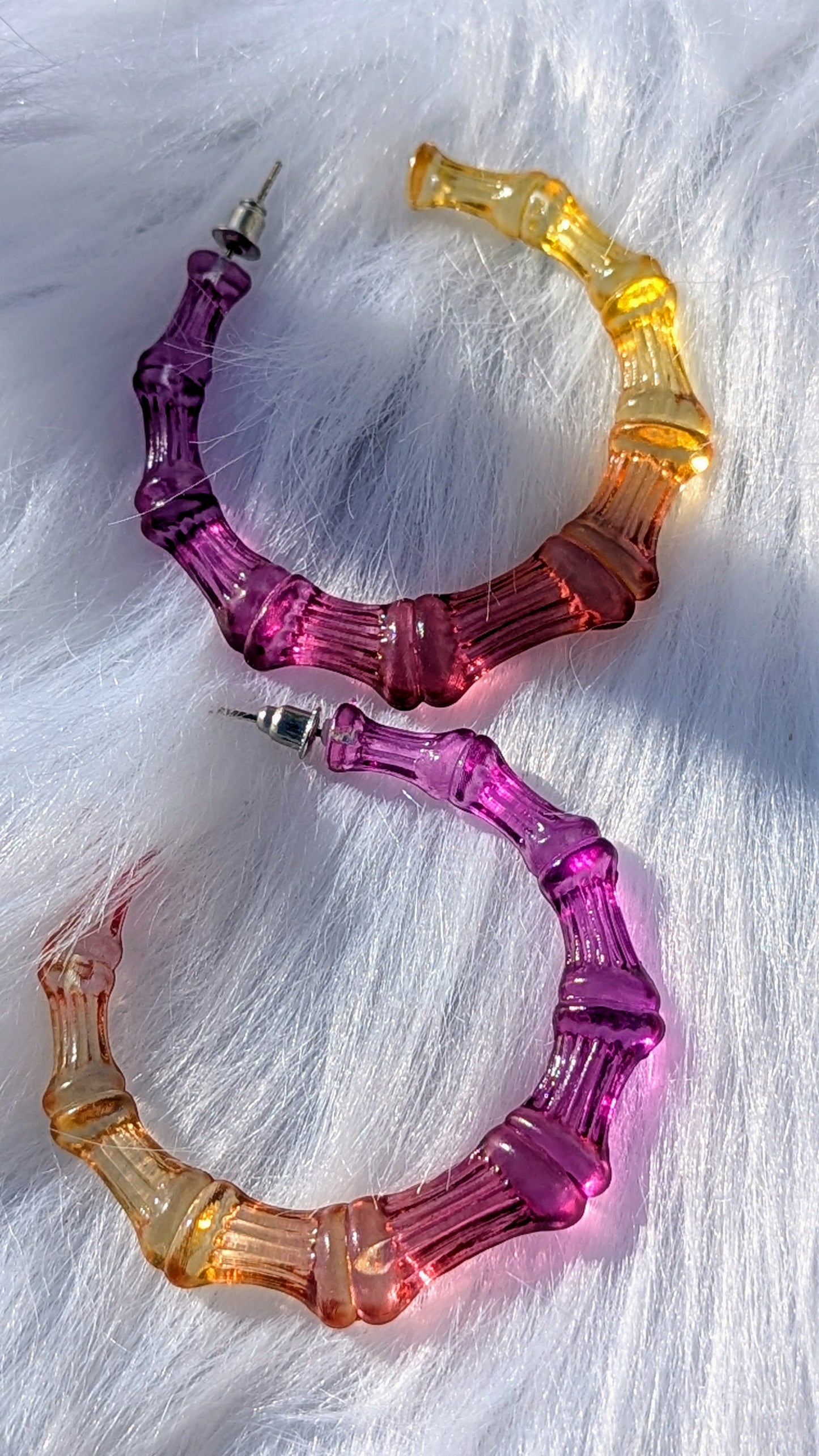 Multicolored hoop earrings on a white fur background