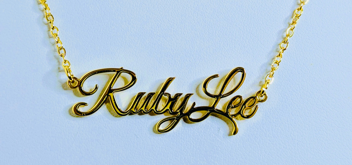 Gold name necklace with 'Ruby Lee' on a light blue background