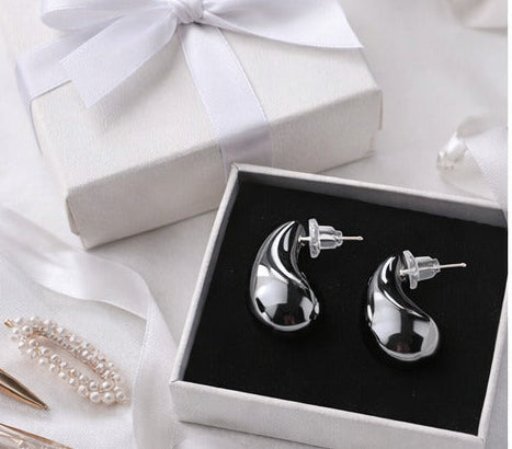 Collage of silver earrings on a white background with close-ups and packaging.