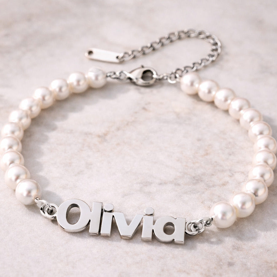 Pearl bracelet with a silver nameplate on a light marble background