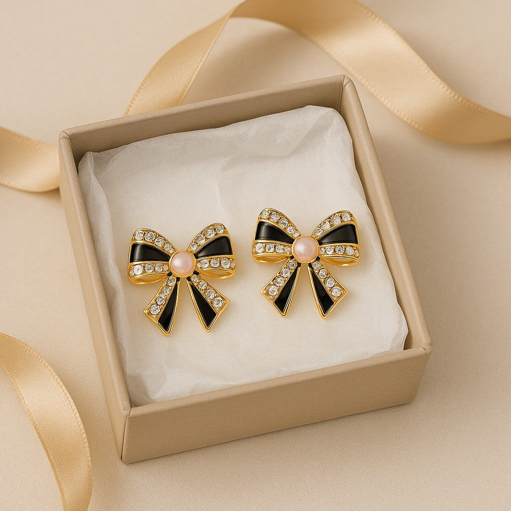 Bow-shaped earrings with black and gold design in a box with a ribbon