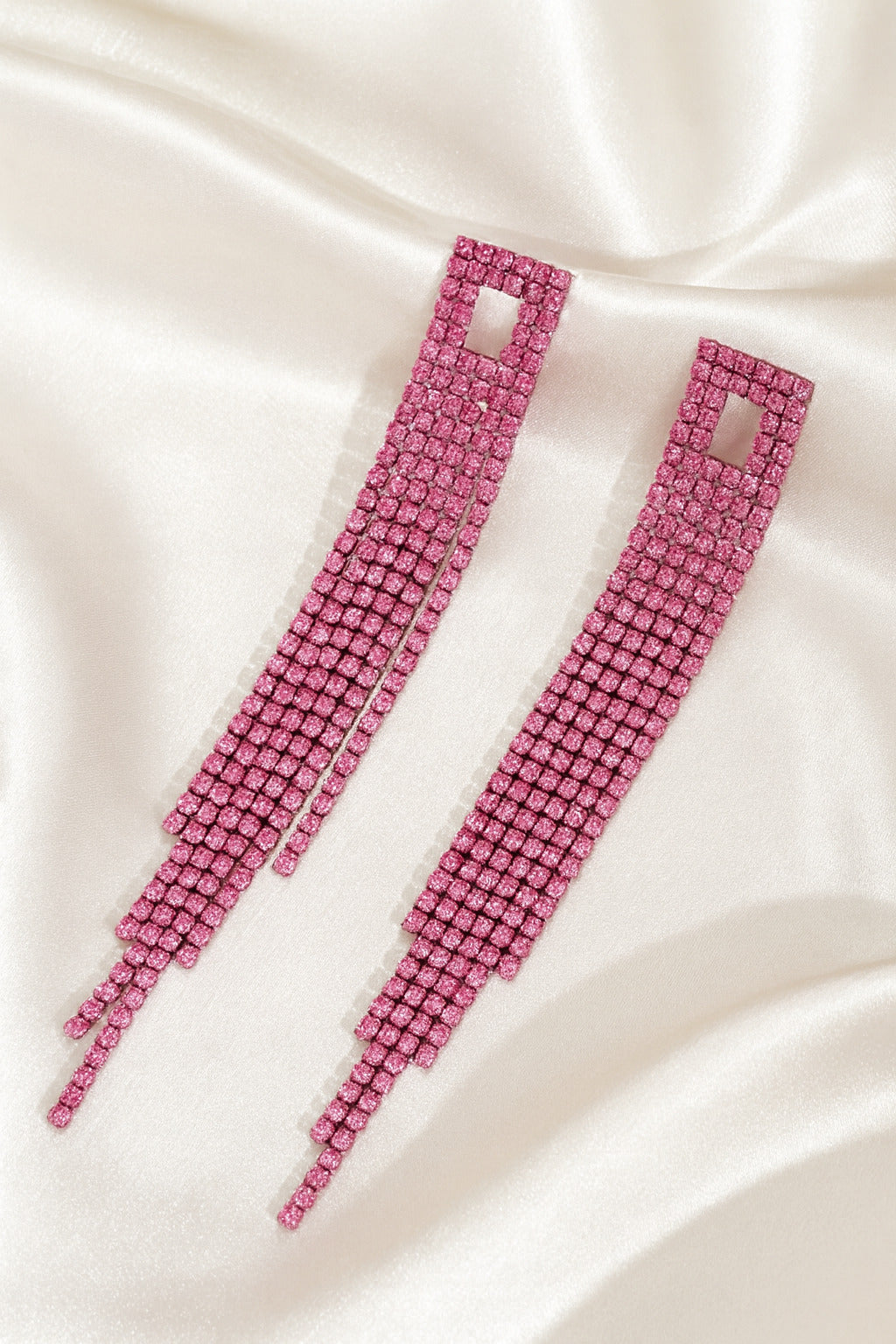 Pink beaded earrings on a satin surface