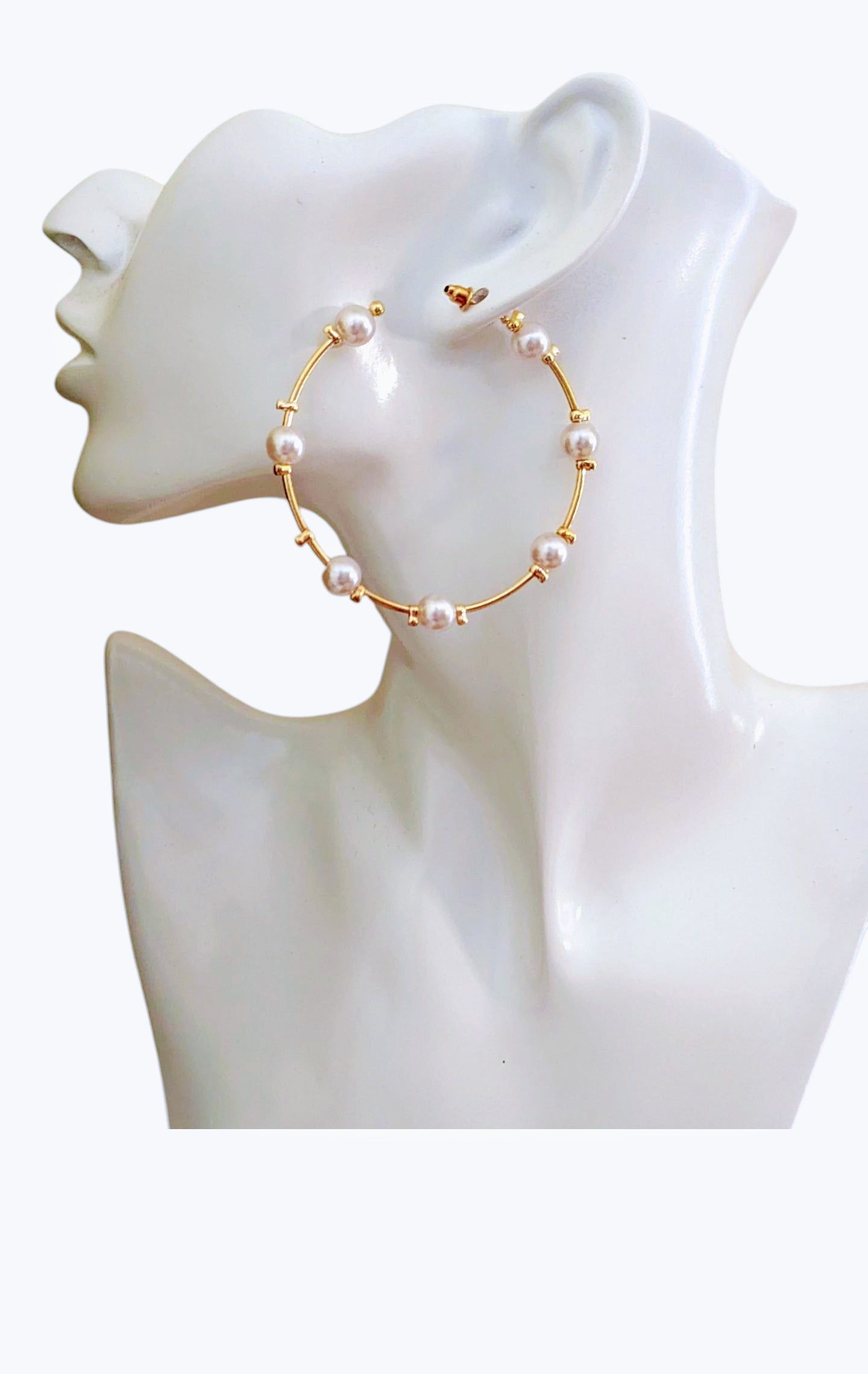 Gold hoop earrings with pearls on a mannequin bust.