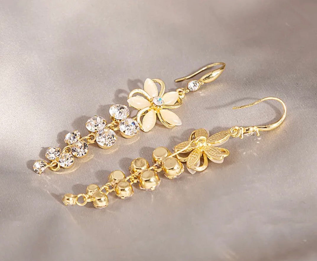 Gold floral earrings with crystal accents on a gray background