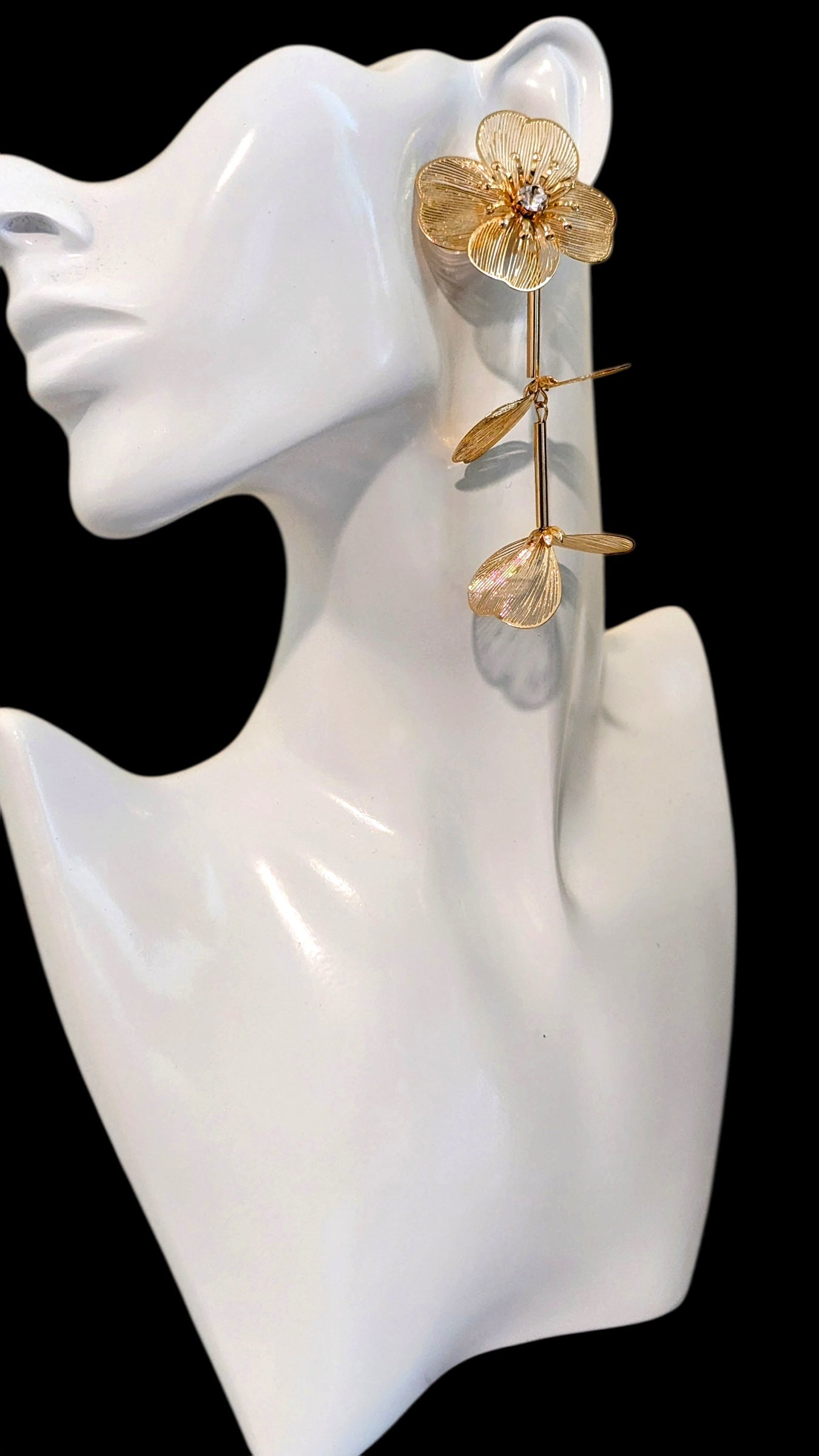 Gold flower earring on a white mannequin head against a black background