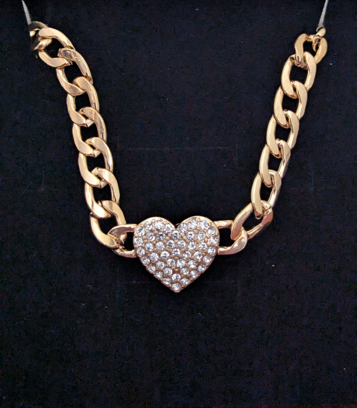 Gold chain necklace with a heart-shaped pendant on a black background