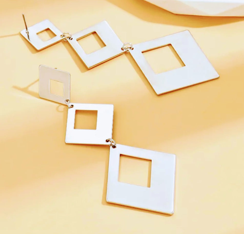 silver square earrings on a yellow background