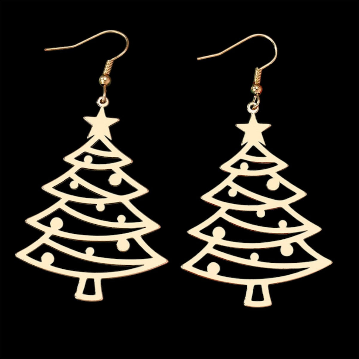 A pair of gold-colored christmas tree-shaped drop earrings against a black background.