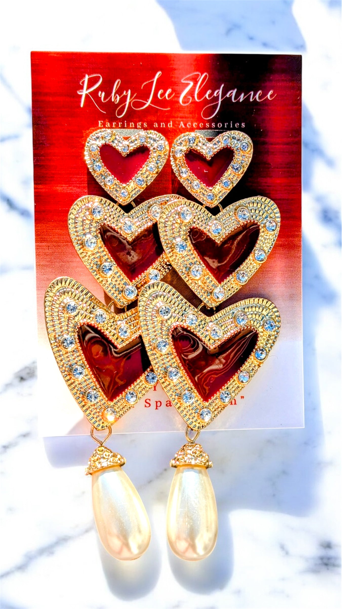 Heart-shaped earrings with gold accents on a Ruby Lee Elegance card.