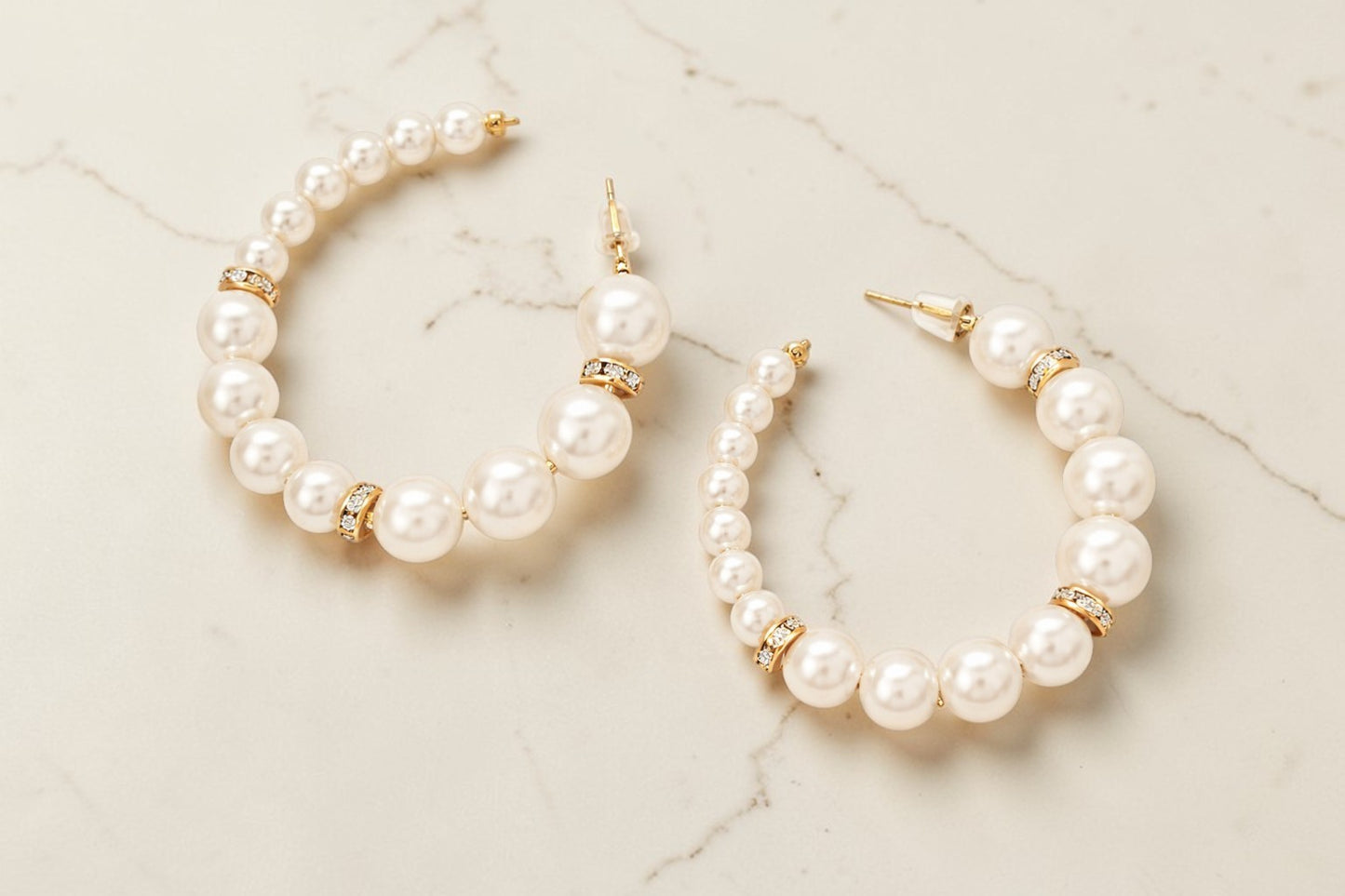 Pearl hoop earrings on a marble surface