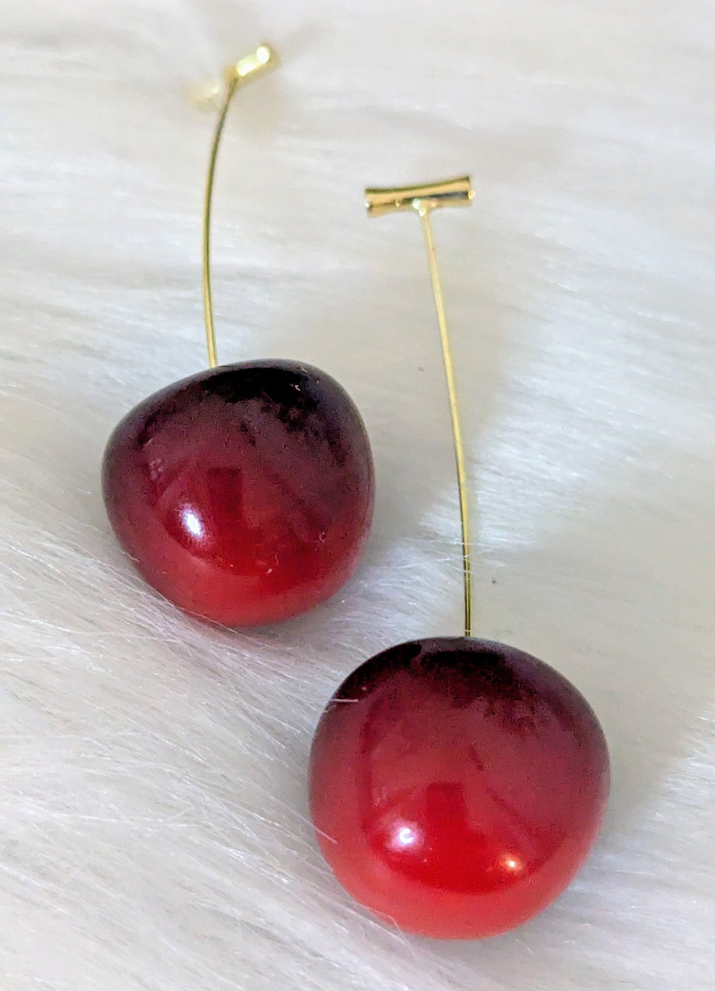 Pair of red cherry-shaped earrings on a white background