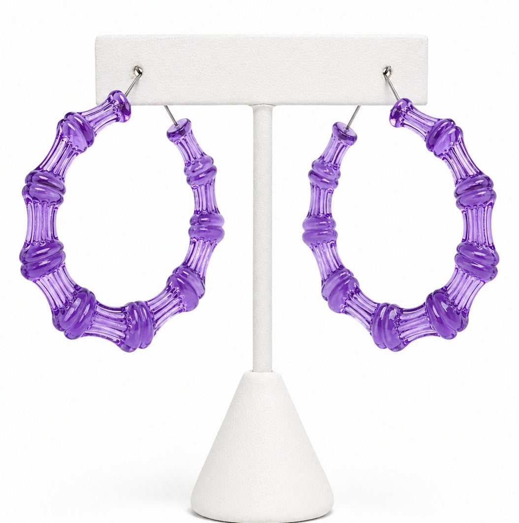 Purple bamboo hoop earrings on a white stand against a white background