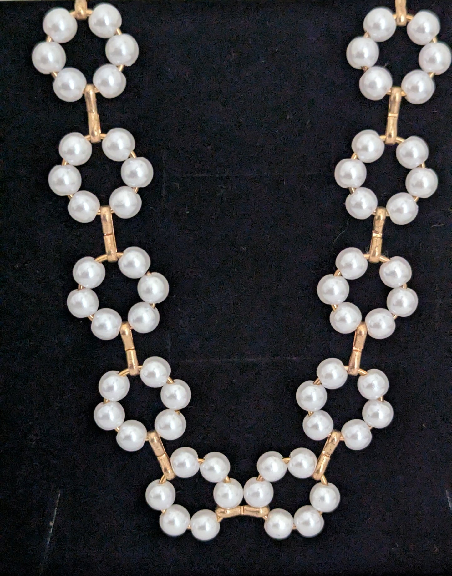 Pearl necklace with gold accents on a black background
