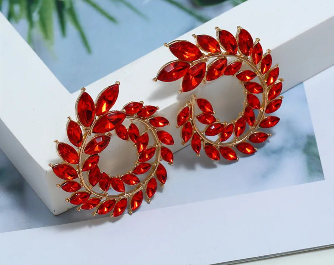 Red gemstone earrings on a white surface with a blurred background