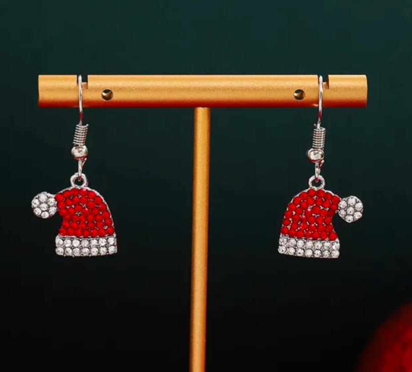 Santa hat earrings on a wooden stand with a dark background