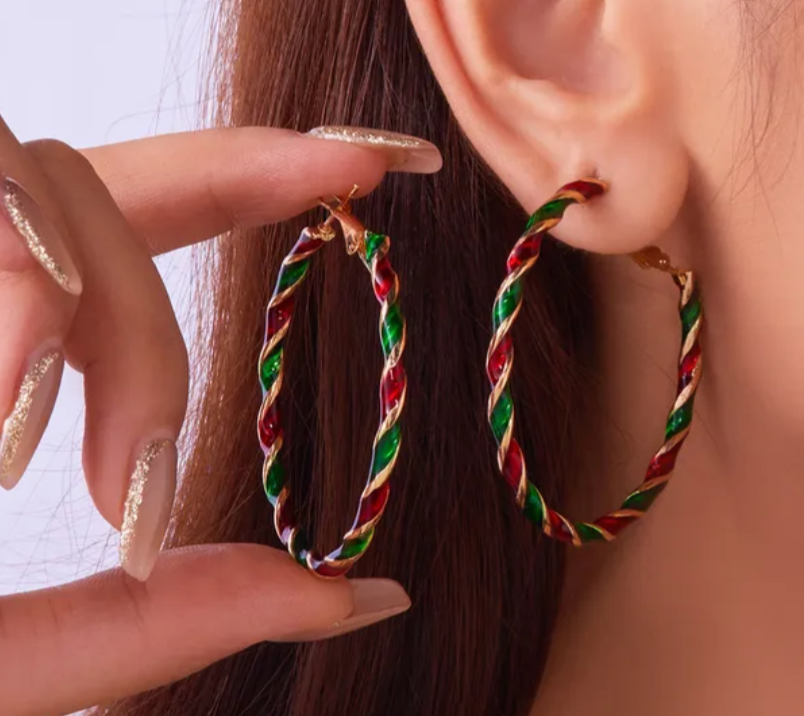 Close-up of a person wearing colorful hoop earrings with a hand pointing to one.