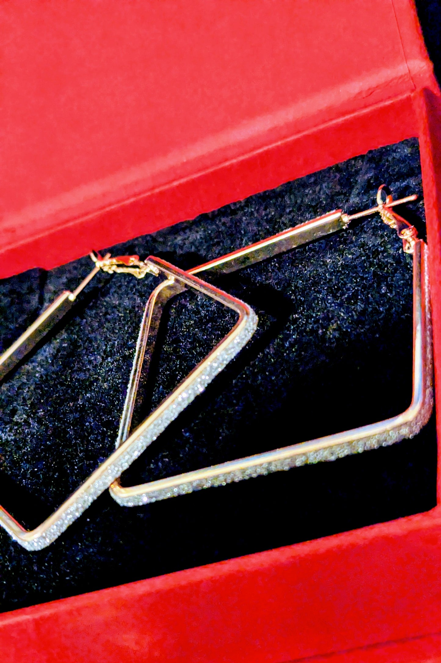 Gold hoop earrings in a red jewelry box with a black interior