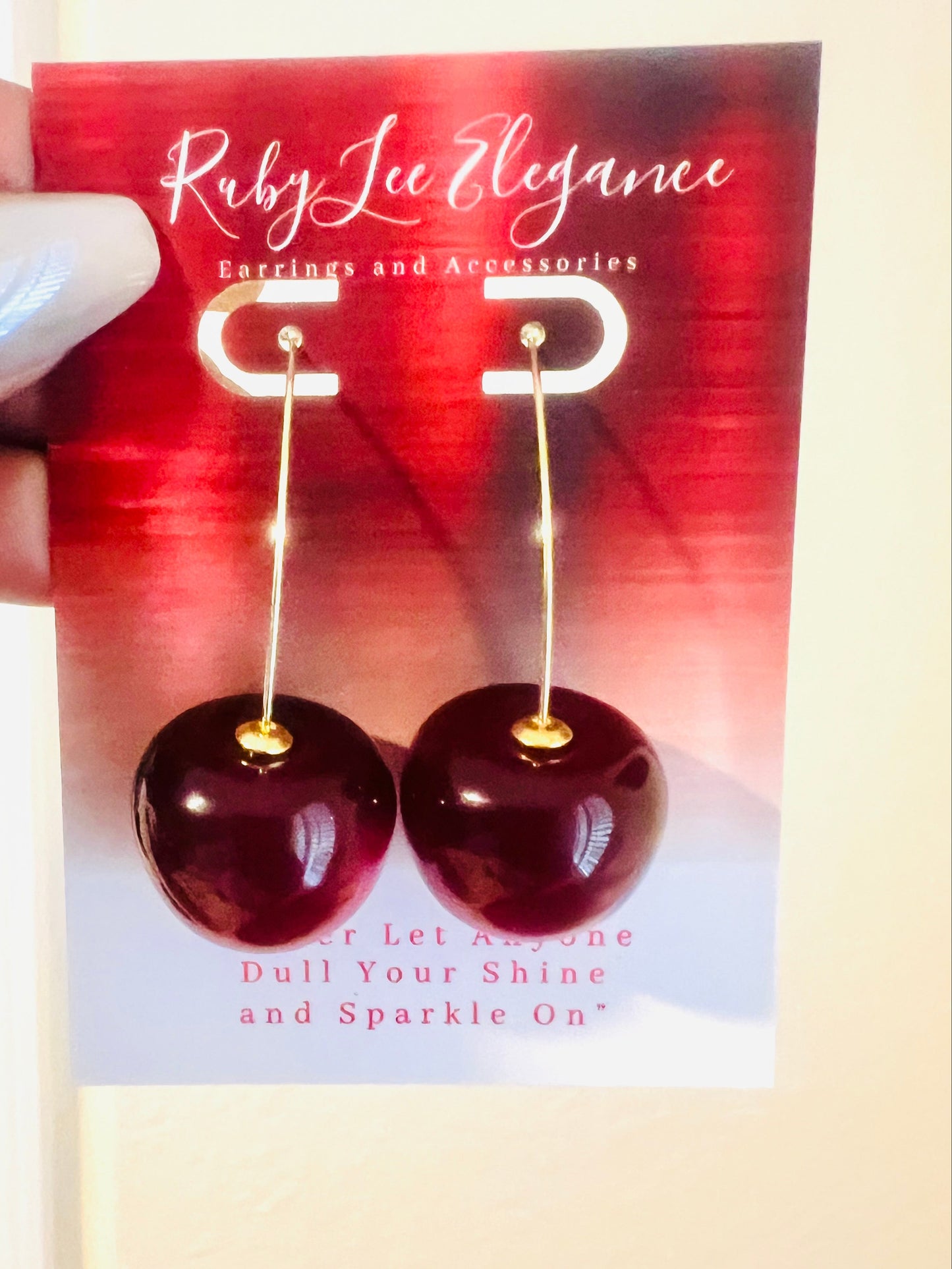 Ruby Lee Elegance earrings on a promotional card held by a hand.