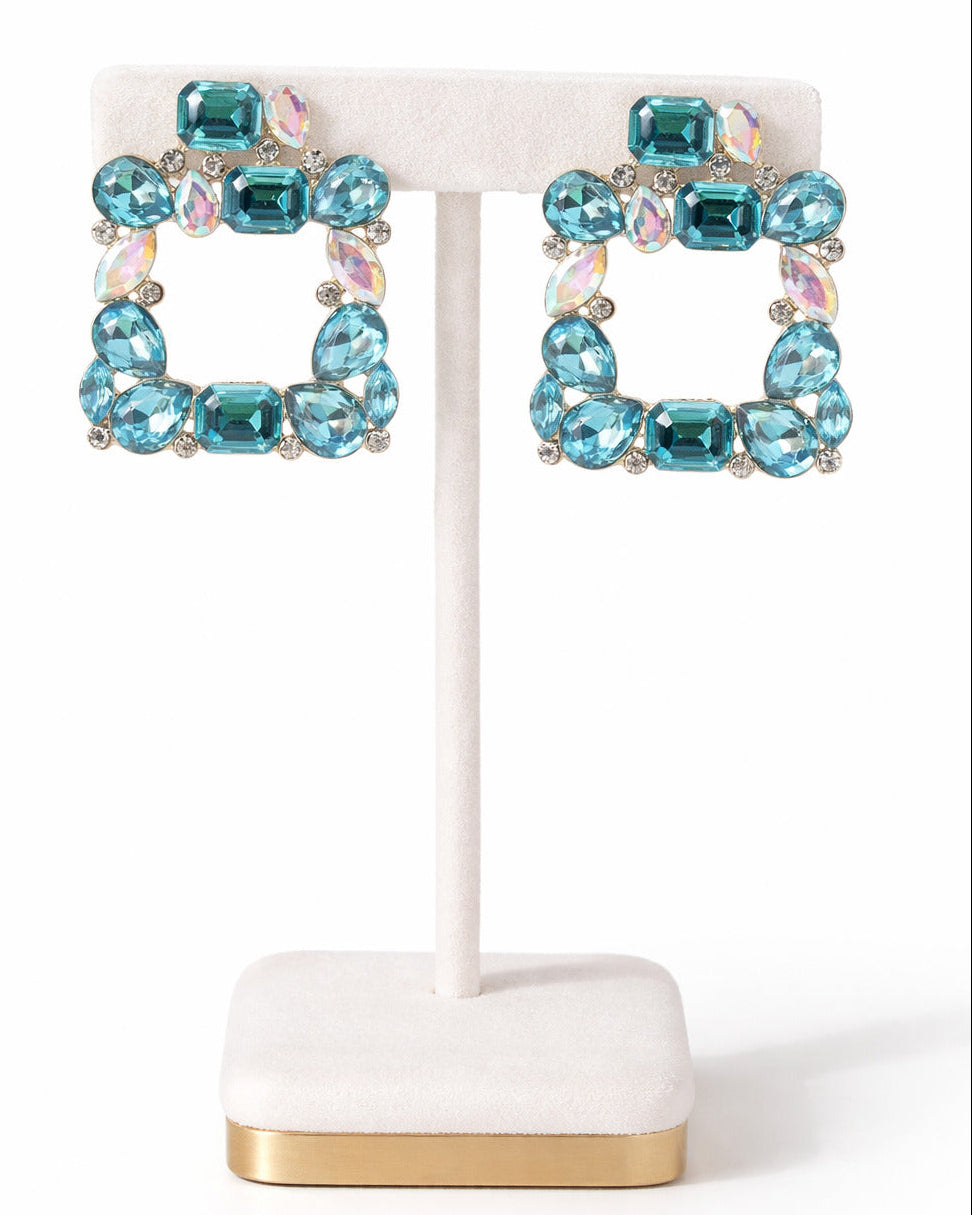 Turquoise beaded earrings on a white stand with gold base