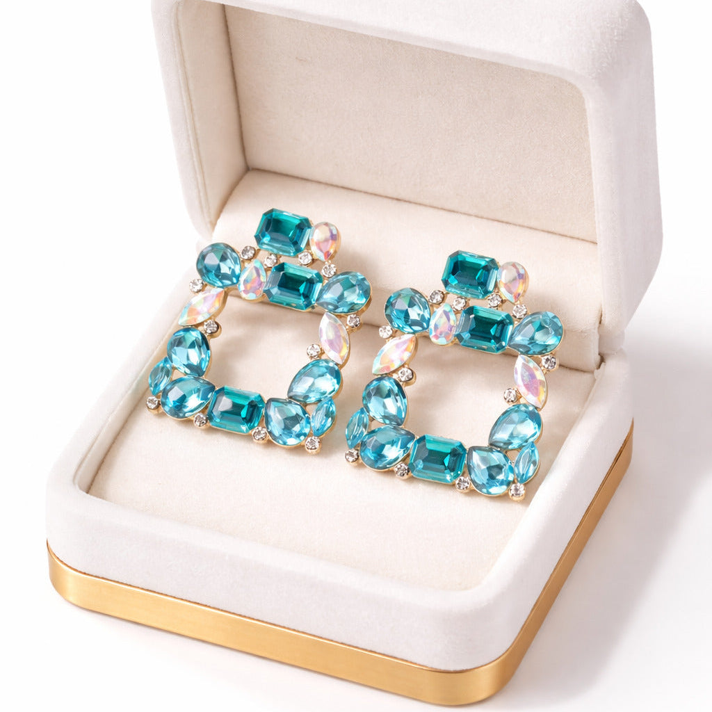 Turquoise gemstone earrings in a white jewelry box with gold accents.