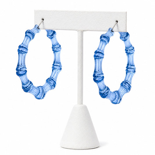 Blue bamboo-style earrings on a white stand against a white background