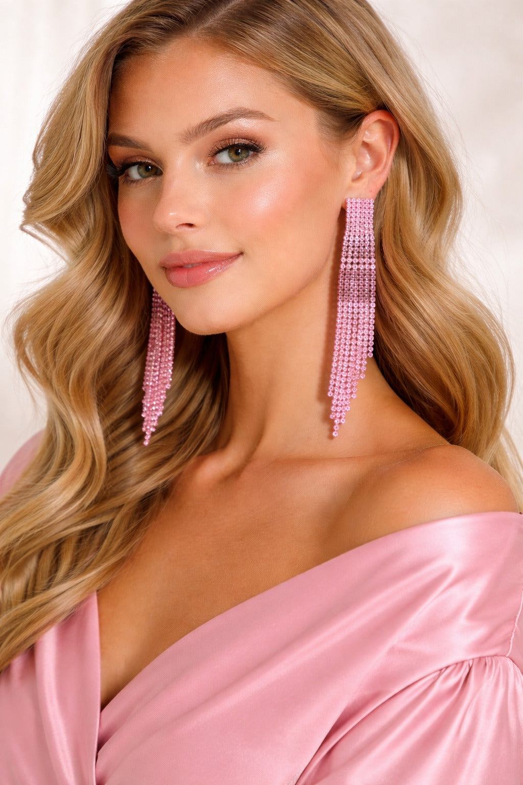 Woman wearing pink beaded earrings and a pink top against a light background