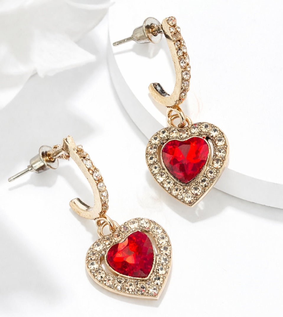 Heart-shaped earrings with red gemstones on a white satin background