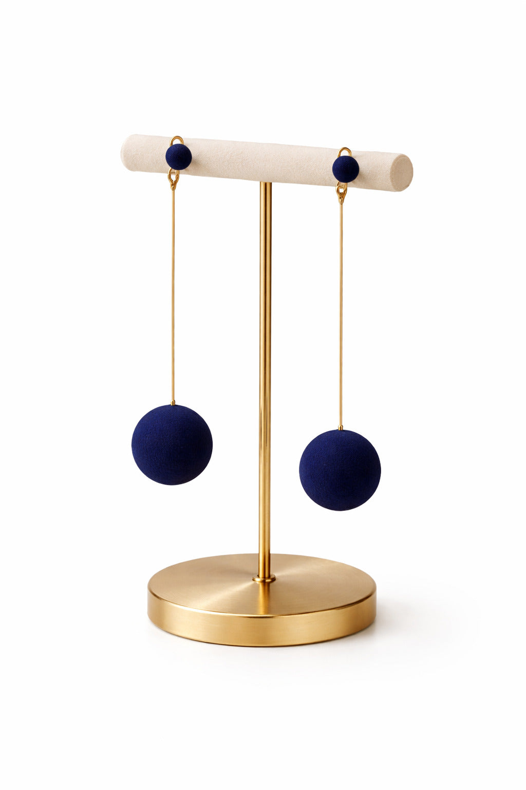 Pair of navy blue earrings on a gold stand against a white background