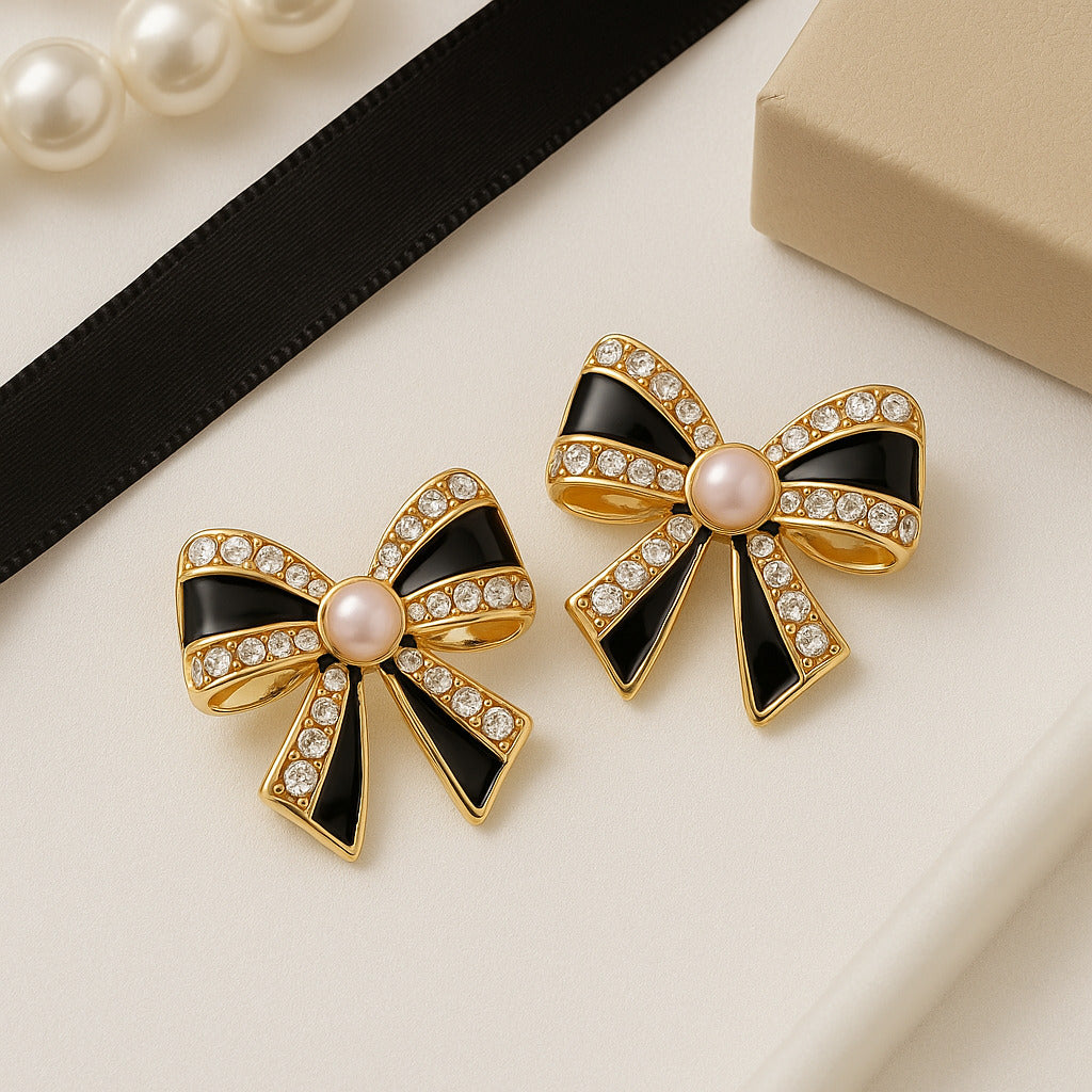 Bow-shaped earrings with black and gold design on a light surface