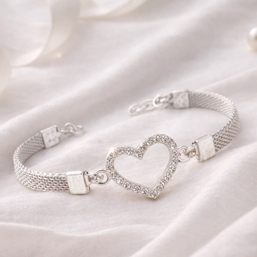 Silver bracelet with a heart charm on a white fabric background