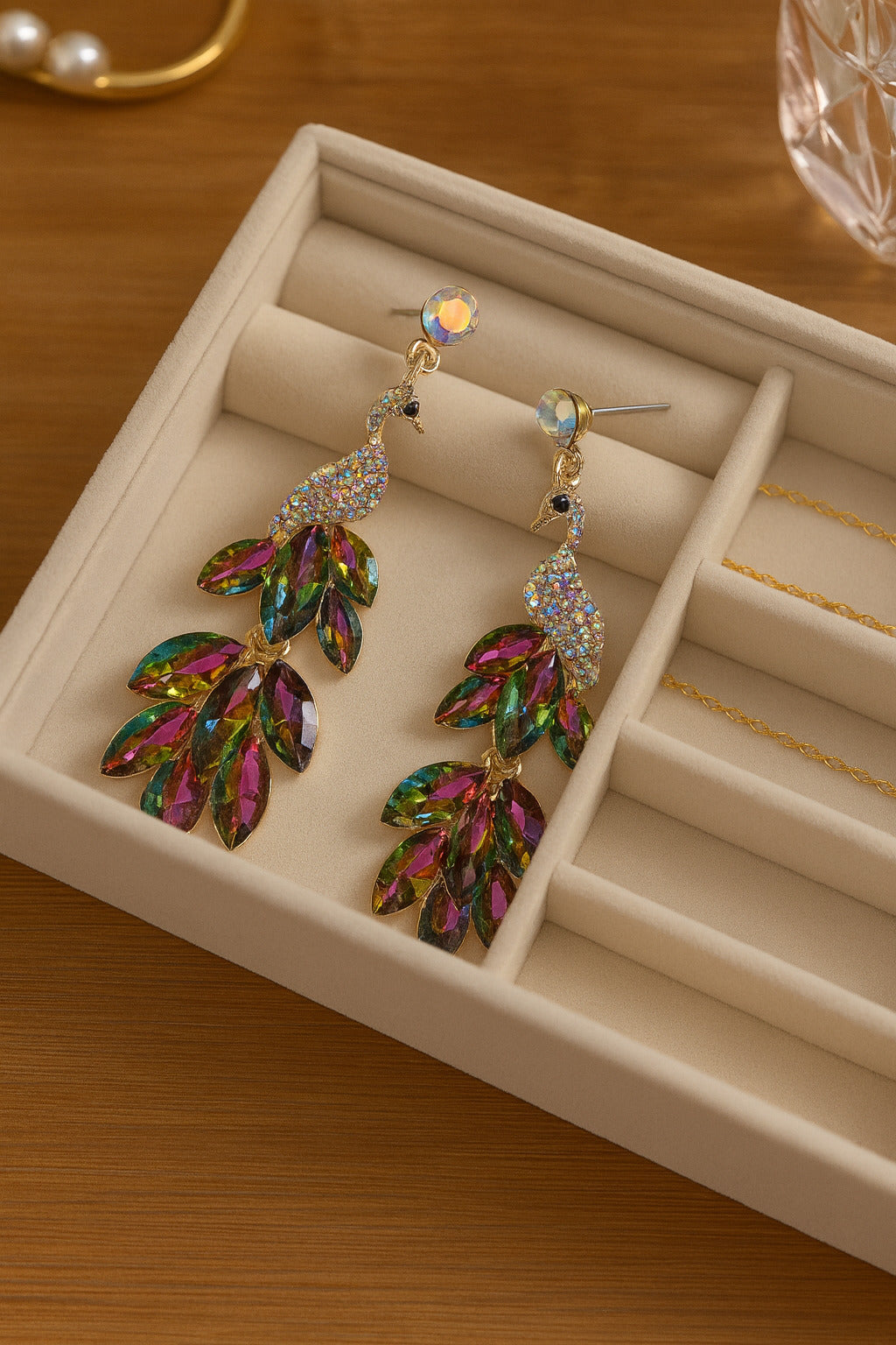 Multicolored leaf-shaped earrings in a jewelry box on a wooden surface