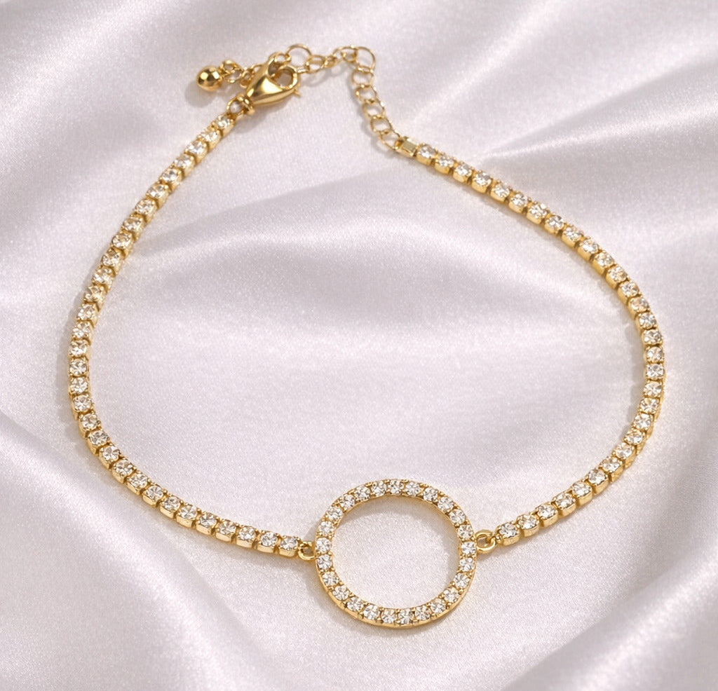Gold necklace with a circular pendant on a satin surface