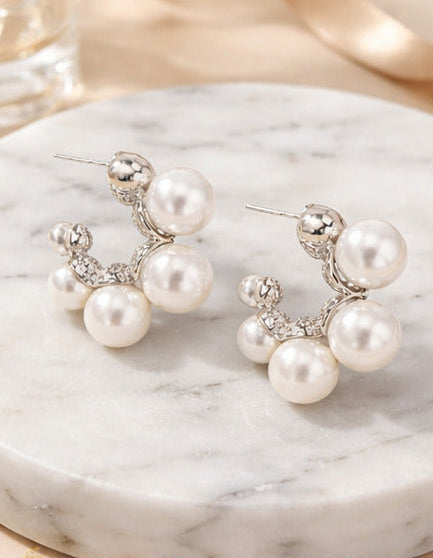 Pearl earrings displayed on a white background, in a jewelry box, on a marble tray, and on neutral fabric.