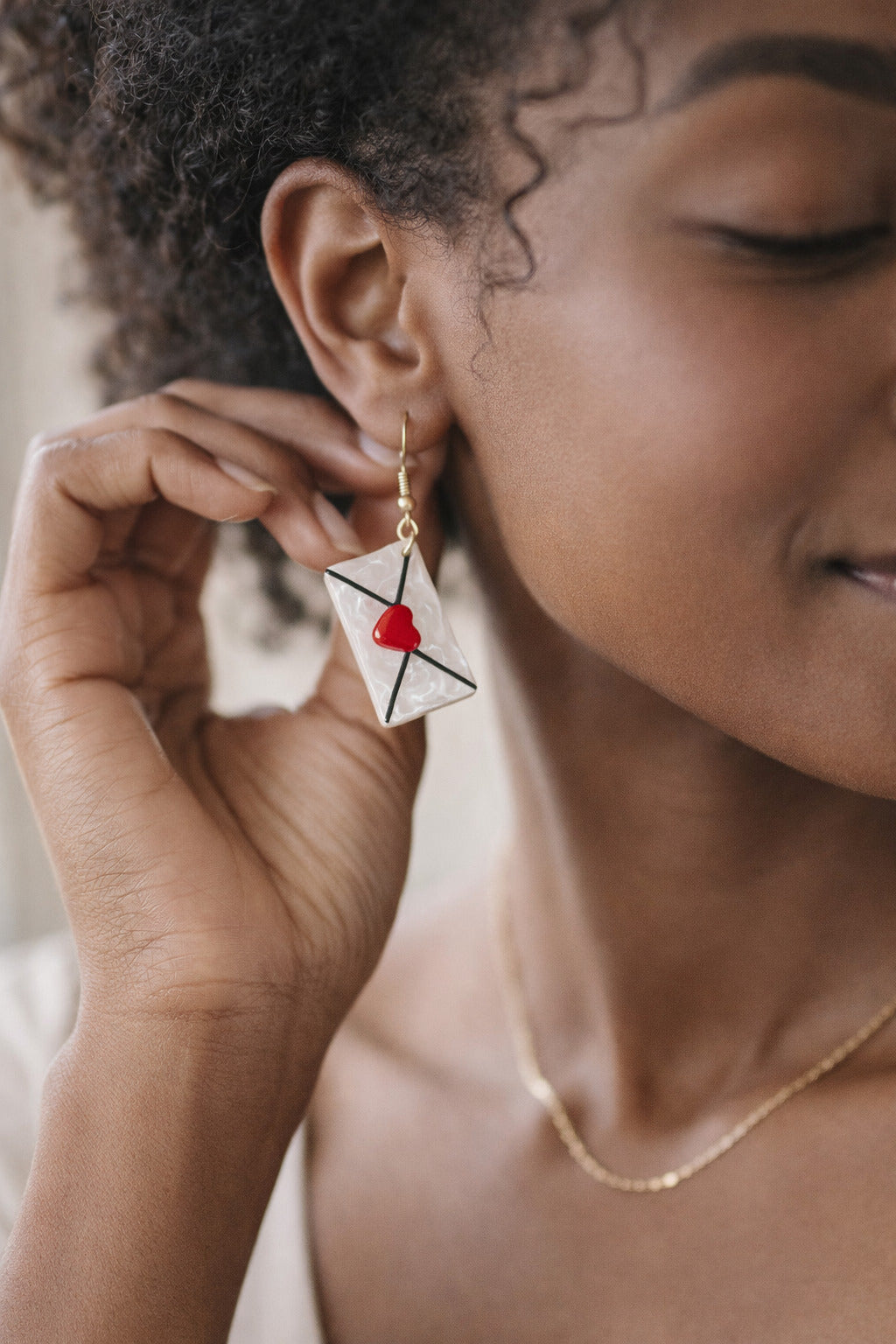 Close-up of a person wearing a unique earring with a red heart design.