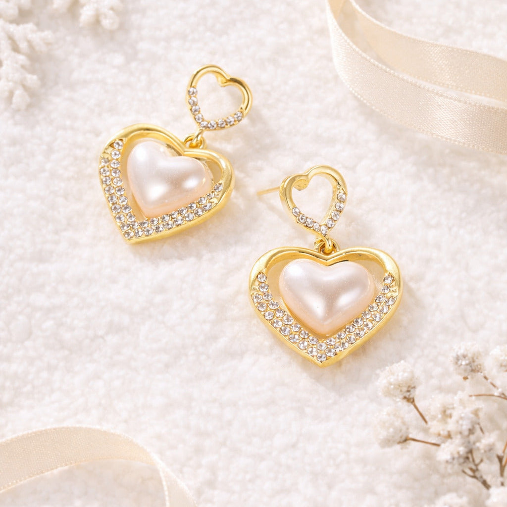 Gold heart-shaped earrings with pearls on a white background