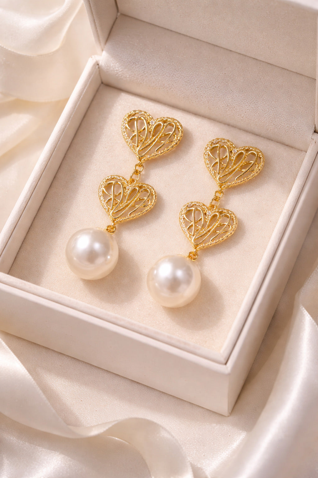 Gold heart-shaped earrings with pearls in a jewelry box