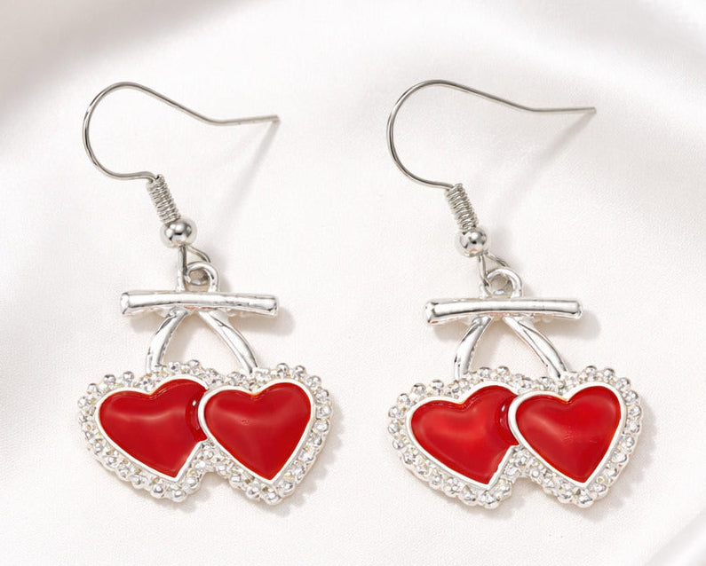 Pair of earrings with red heart designs on a white background