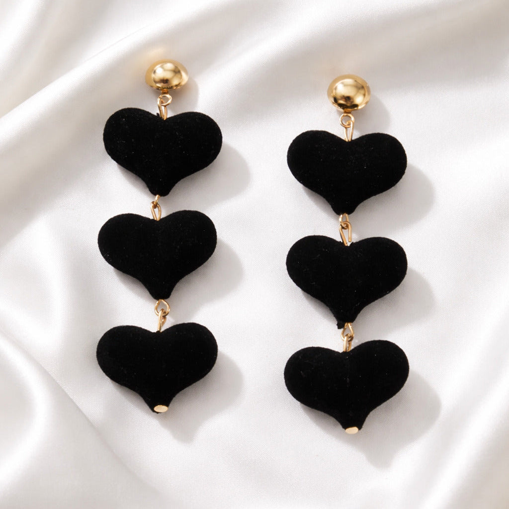 Black heart-shaped earrings on a white fabric background
