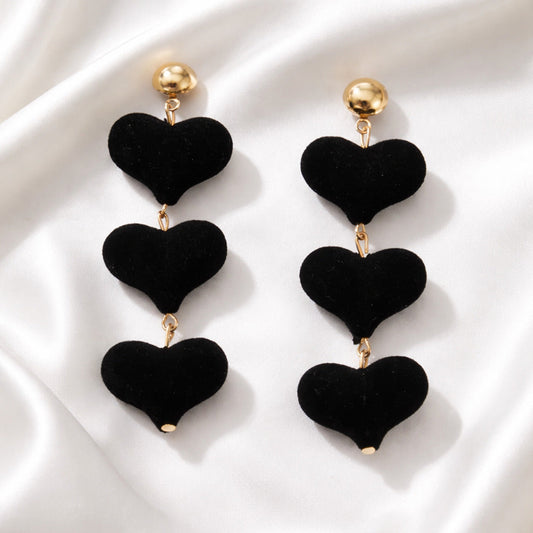 Black heart-shaped earrings on a white fabric background