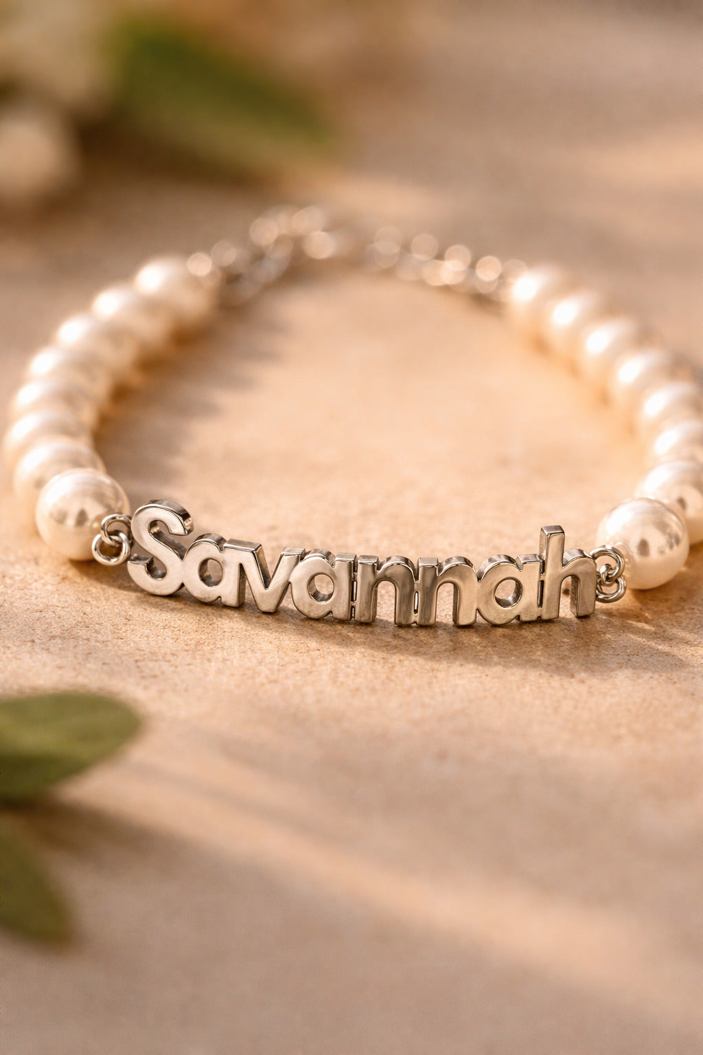 Pearl bracelet with a silver name charm on a beige surface