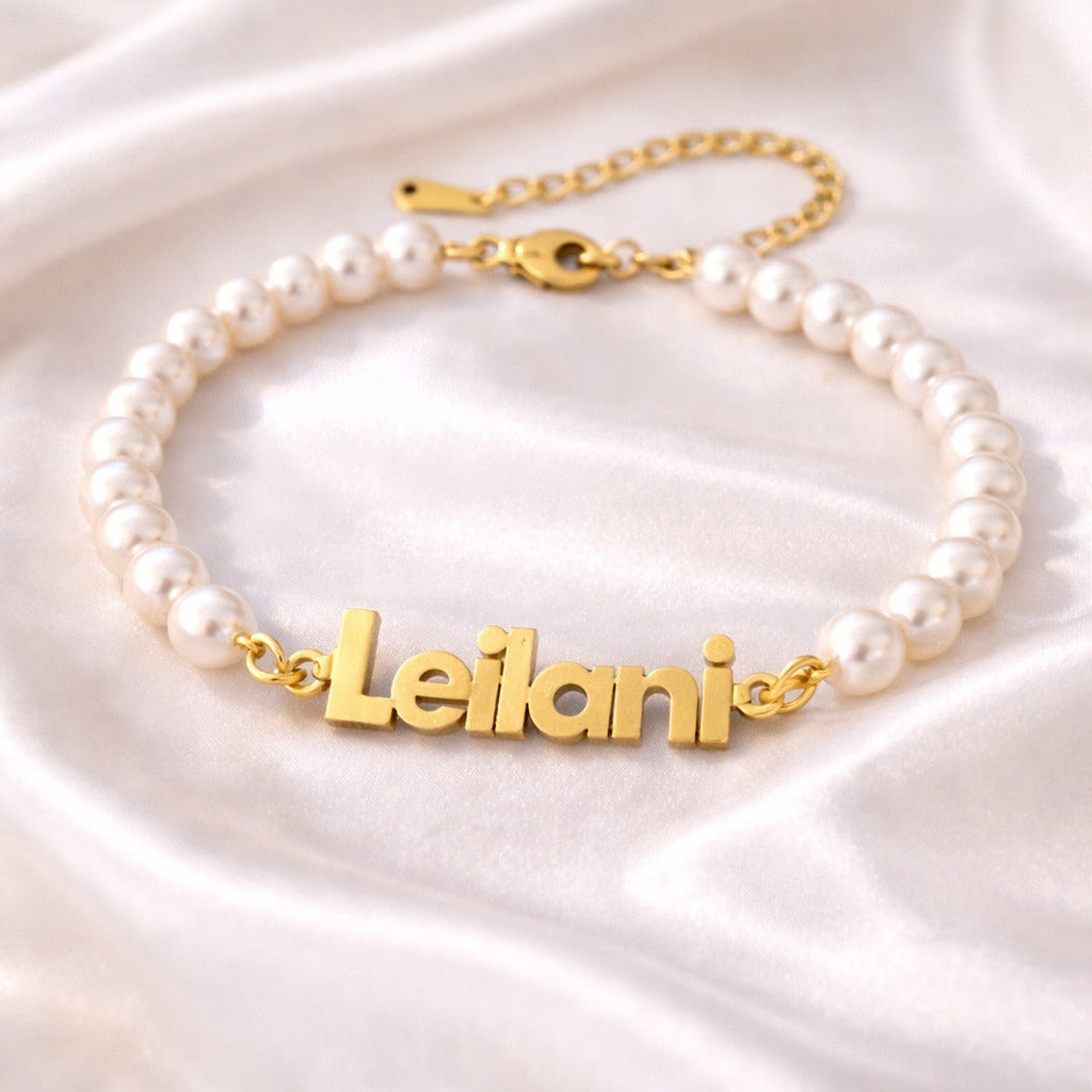 Pearl bracelet with gold nameplate on a satin surface