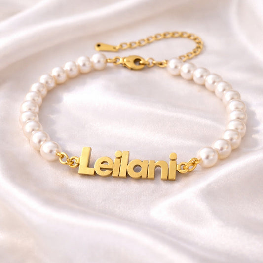 Pearl bracelet with gold nameplate on a satin surface