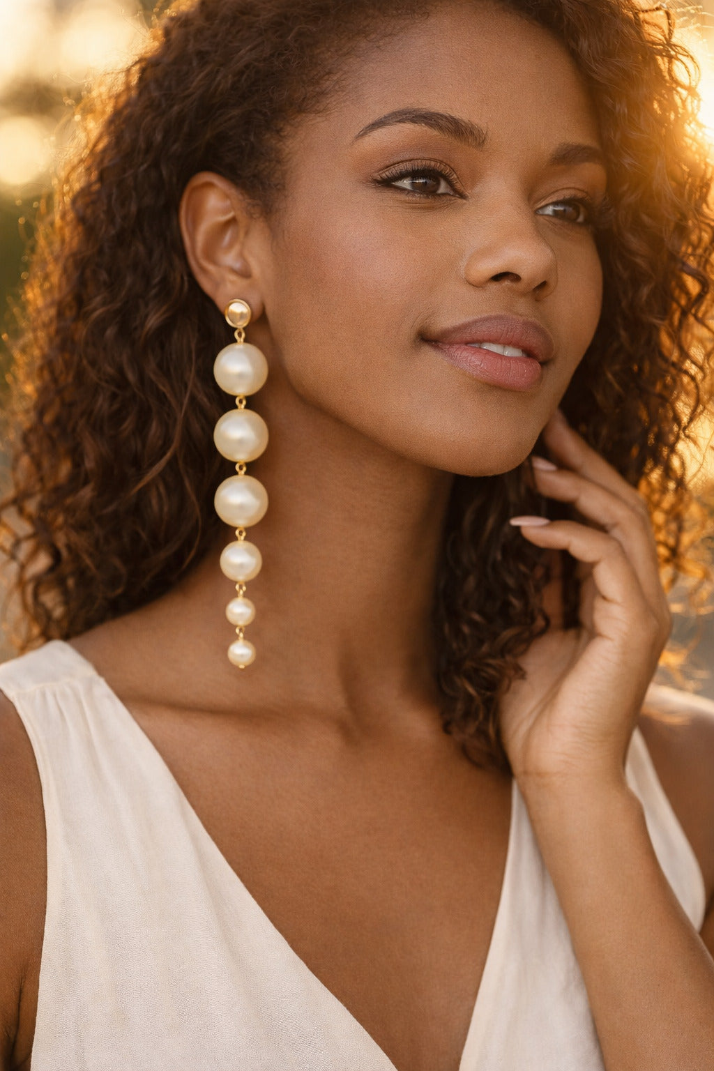 Woman wearing pearl earrings with a blurred natural background