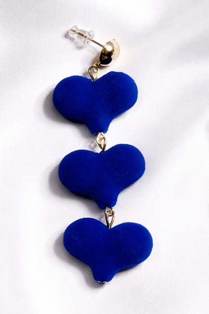 Pair of blue heart-shaped earrings on a white fabric background