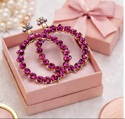 Collage of women wearing pink hoop earrings with close-ups of the jewelry on a pink background.