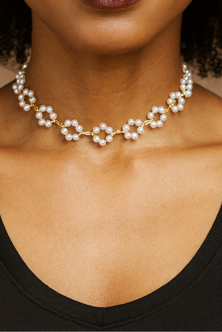Close-up of a person wearing a pearl necklace with a neutral background