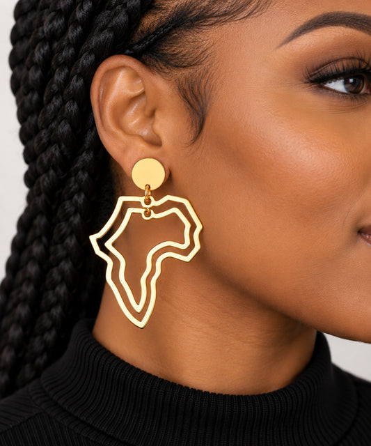 A close-up of a woman wearing a gold-toned dangle earring shaped like the outline of Africa, paired with a black ribbed turtleneck sweater.