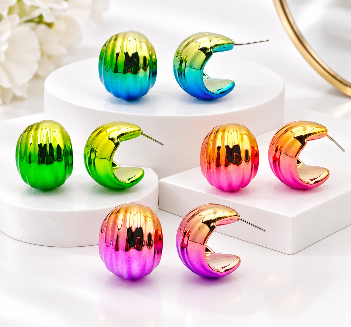 four pairs of iridescent rainbow earrings displayed on white cylindrical pedestals. The set includes two styles: smooth, rounded dome earrings and textured, ribbed crescent moon-shaped earrings with post backs.