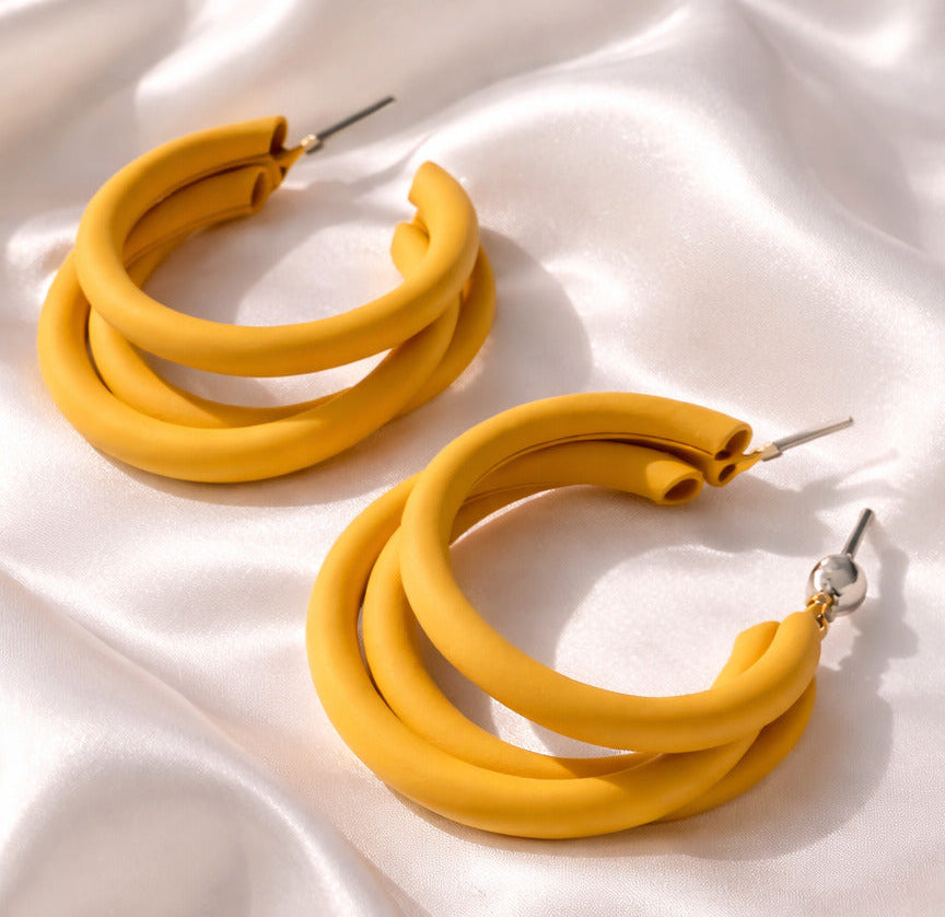 Yellow hoop earrings on a white satin background