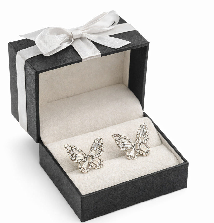 Butterfly-shaped earrings in a black and white striped box with a bow.